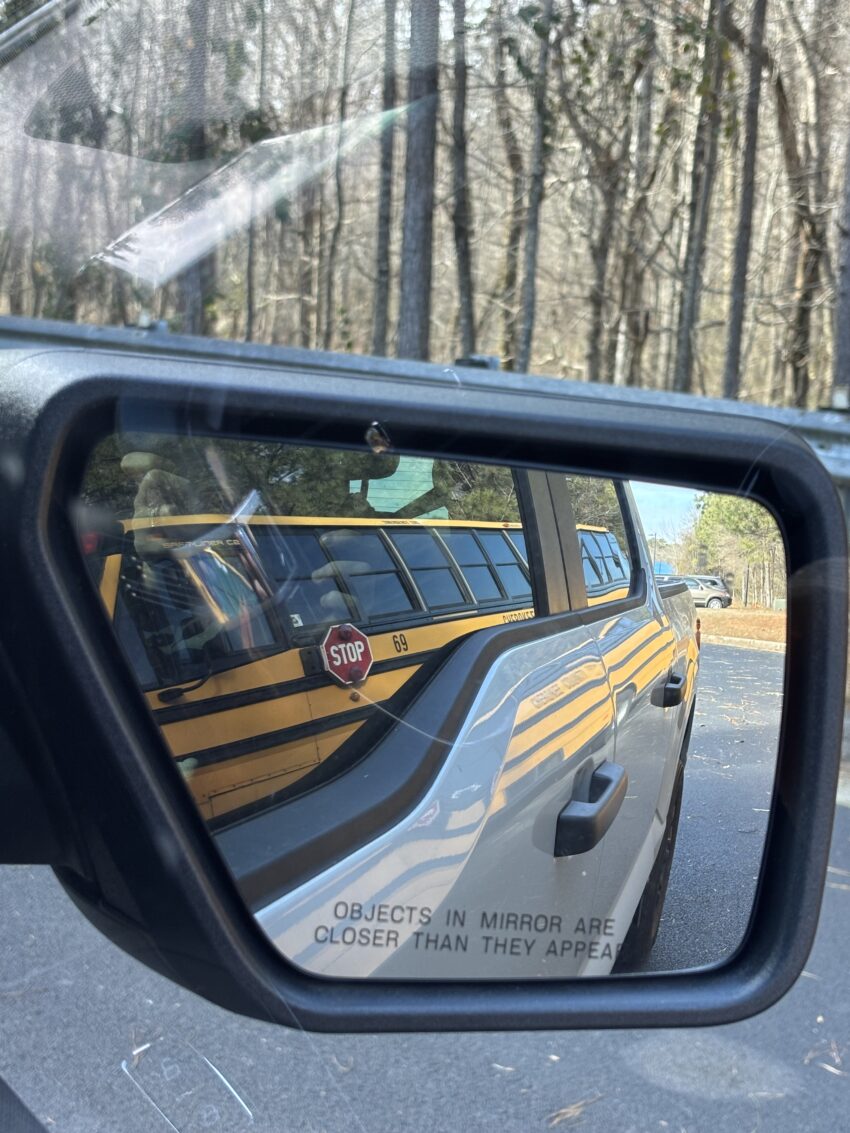 closeup of side mirror with reflection of a bus